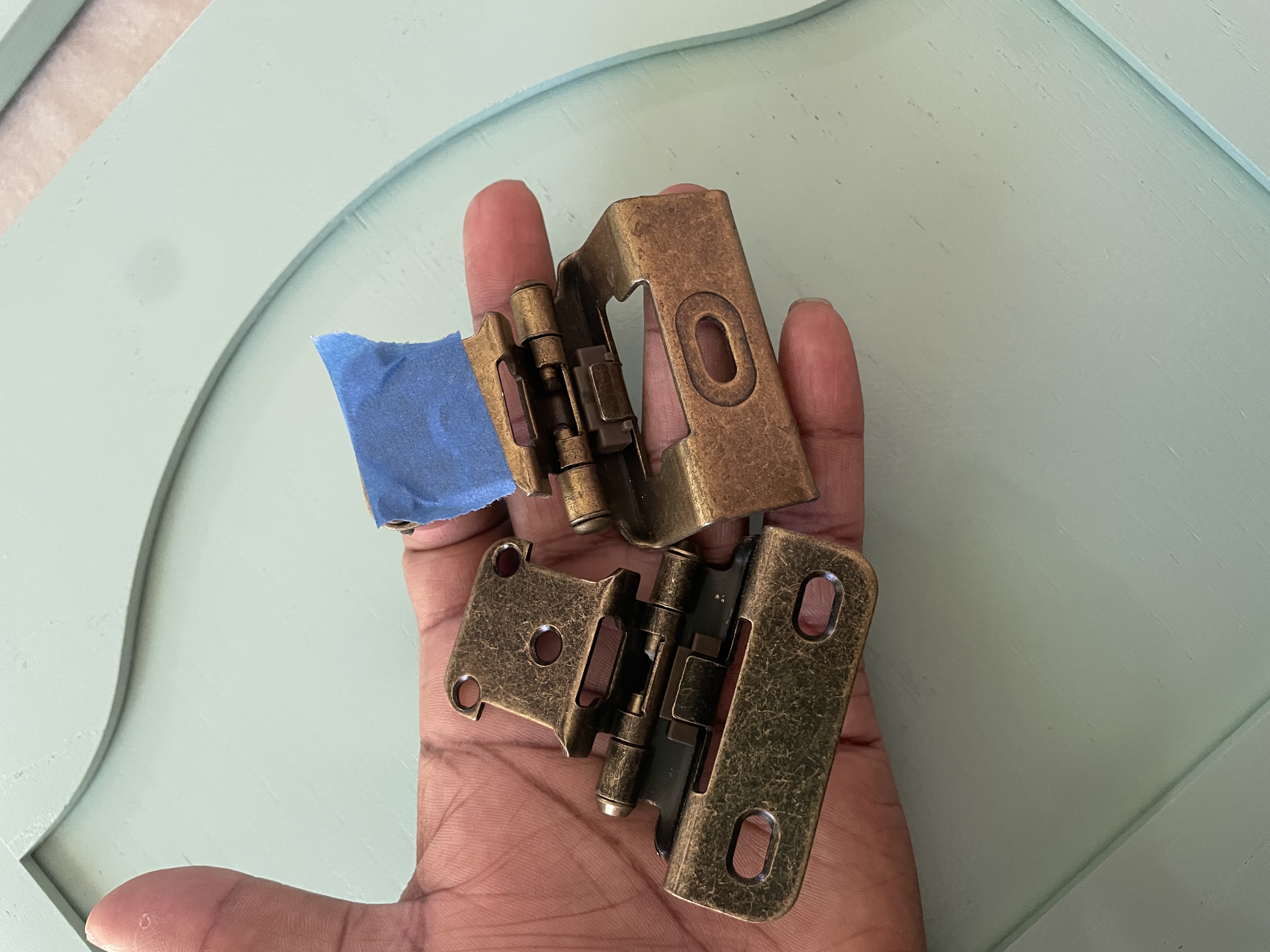 two cabinet door hinges in a hand