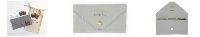 A tan bag with the word FOTO on it. 5 small red and balck SD cards. A white letter and a gray leather sd card wallet.