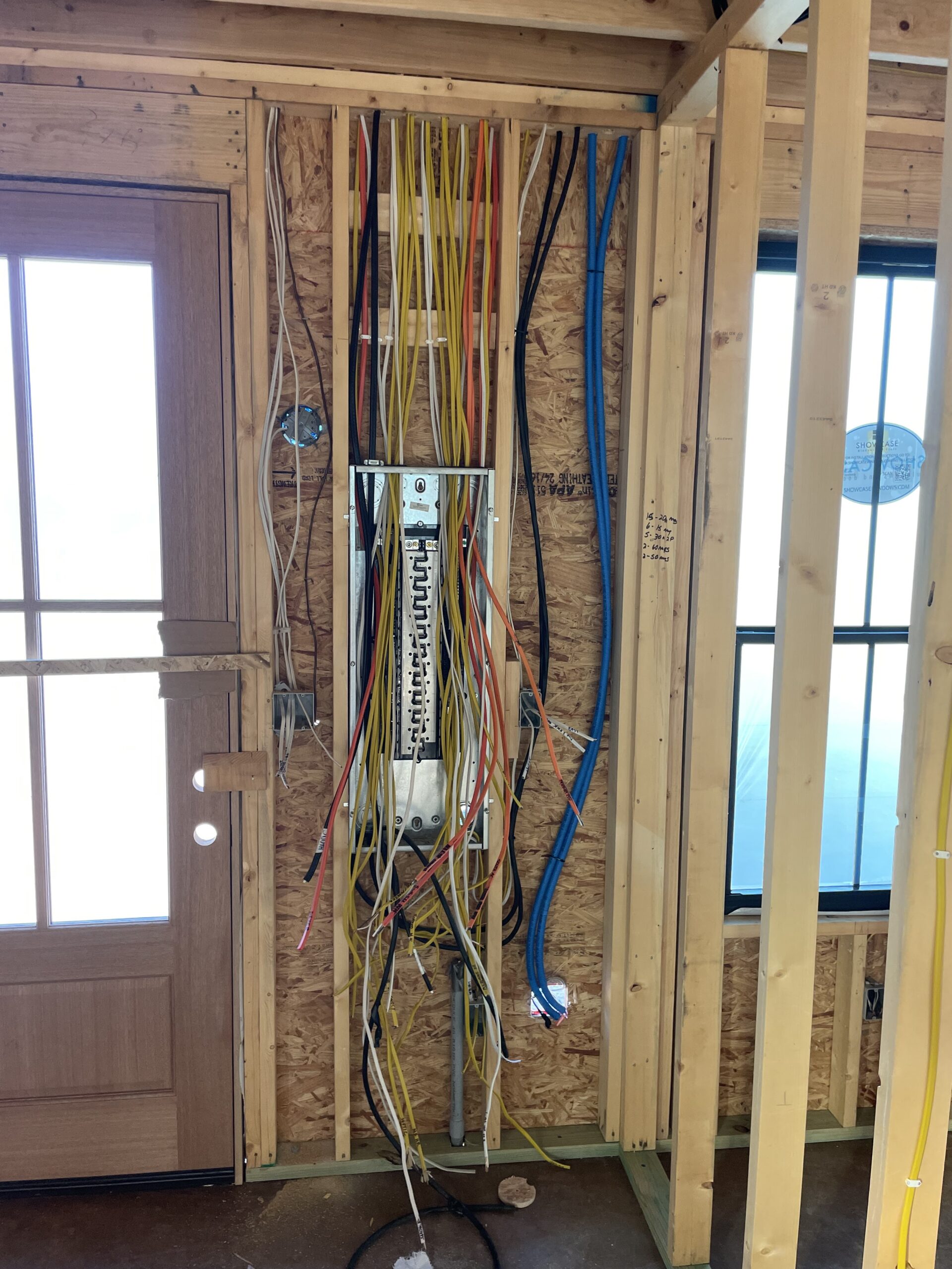 bare wall showing electrical wires entering a breaker box.