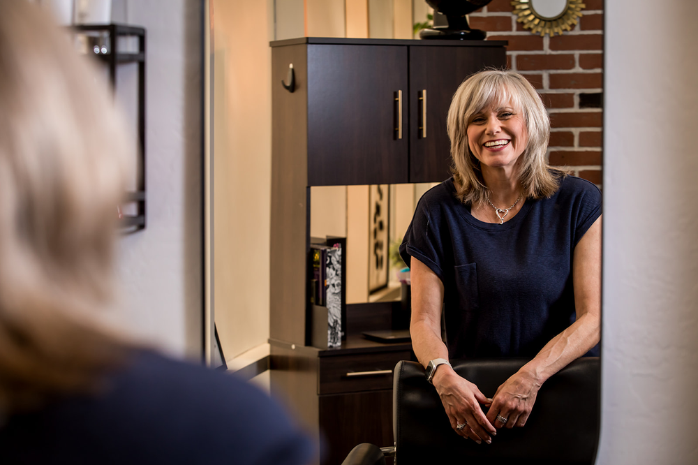 female hairstylist looking in salon mirror