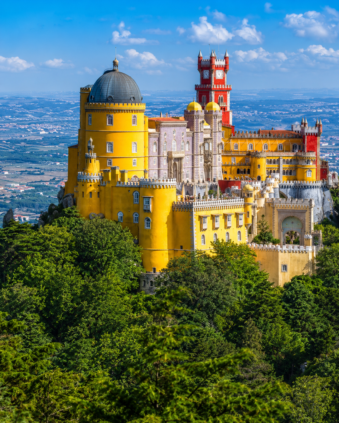 The colorful Pena Palace perched on a hilltop in Sintra, Portugal, with its yellow, red, and blue towers rising above the surrounding forest, a UNESCO World Heritage Site