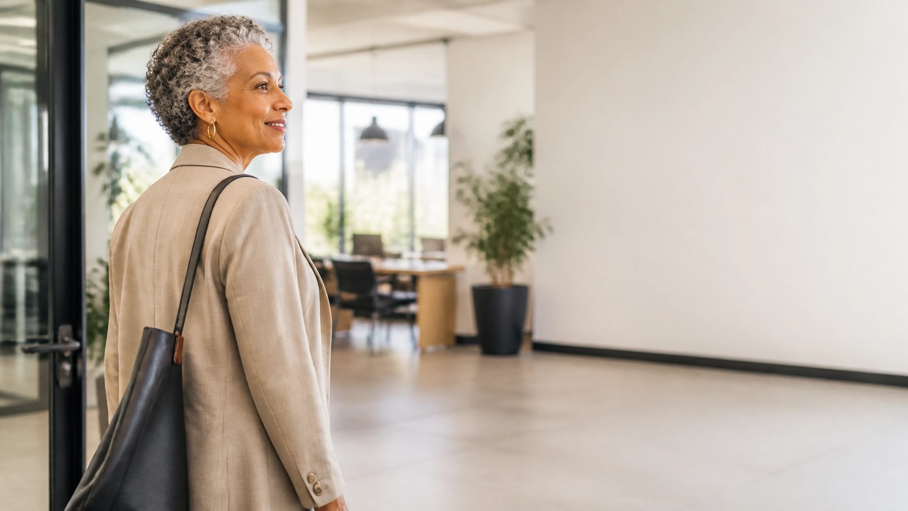 Mature professional woman standing in a bright office and looking toward a new chapter.