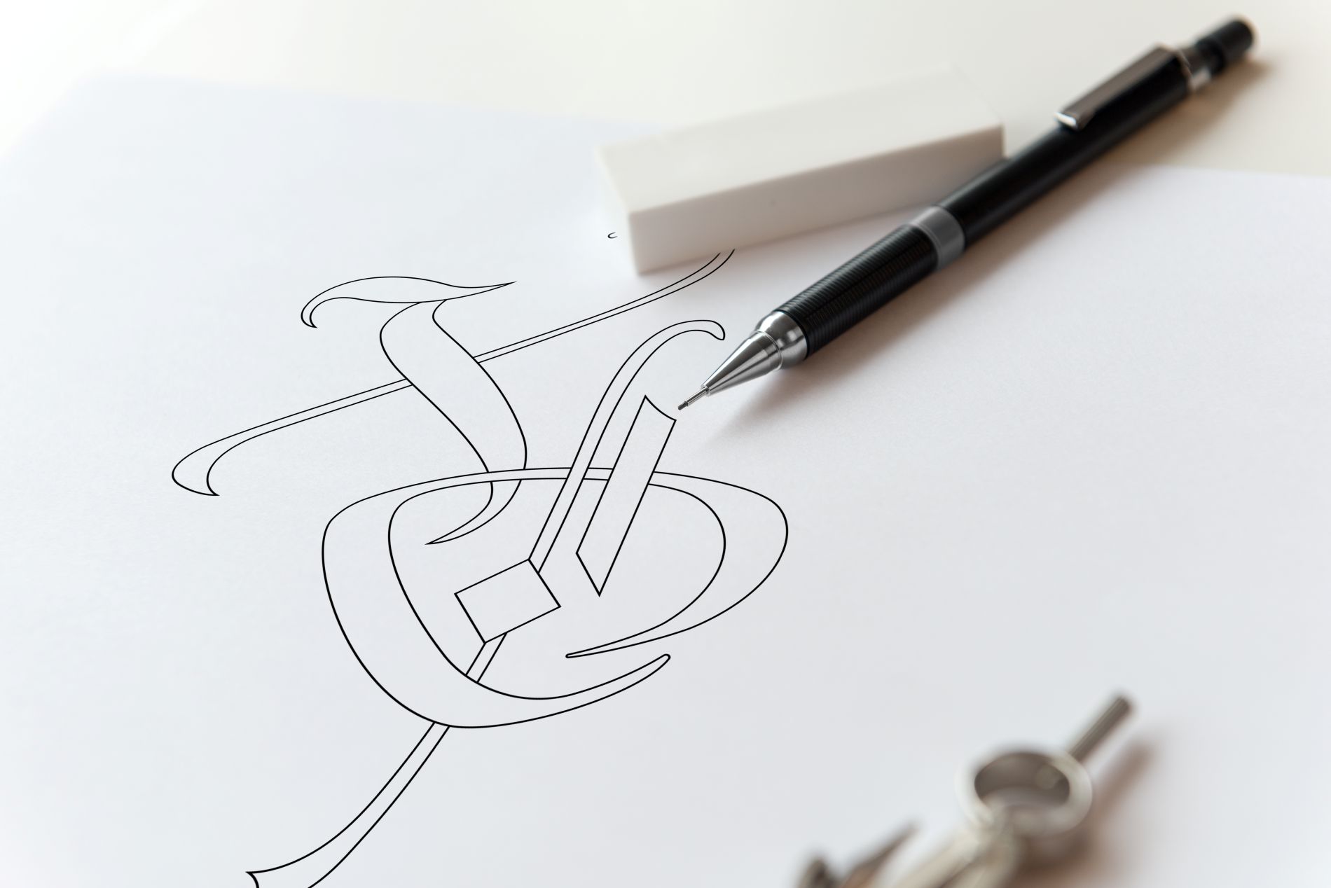 Sketch of gothic-style XO lettering for Luneville embroidery composition, shown with pencil and eraser on white paper