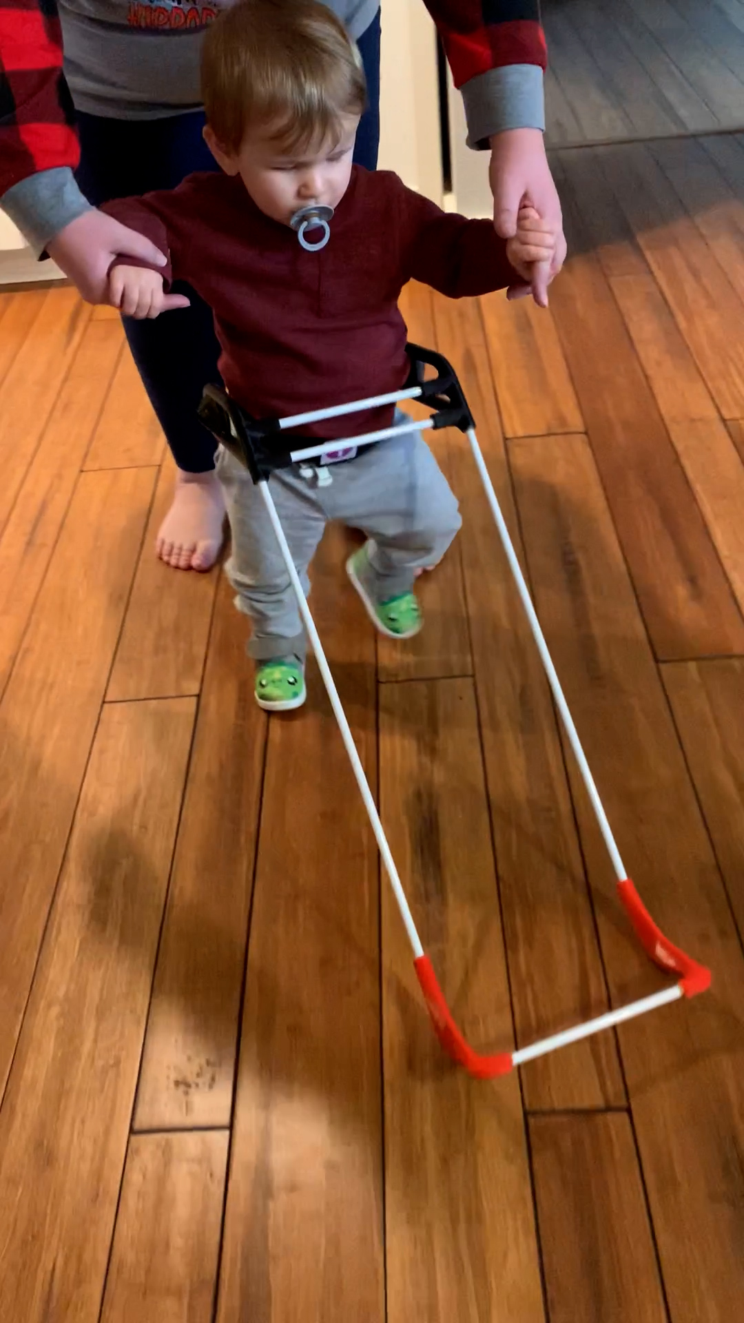 1-year-old boy holds his mom's hands to walk, wears a Belt Cane