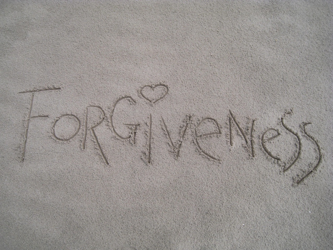 Forgiveness word in the sand