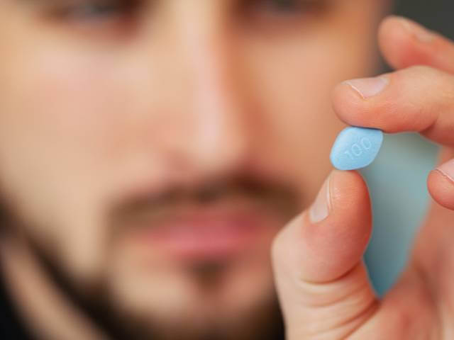 homme tenant une pilule de viagra 50 mg