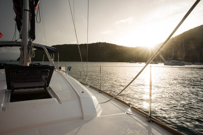 A white boat with a beautiful sun flare in the background.