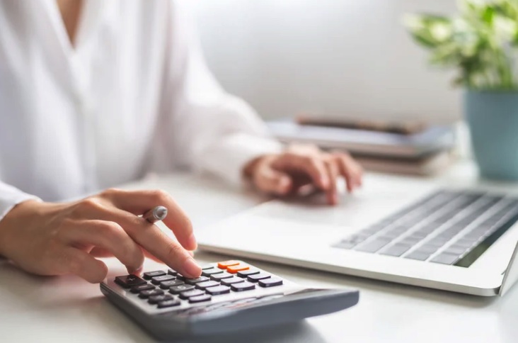 person working on expenses with their laptop and calculator