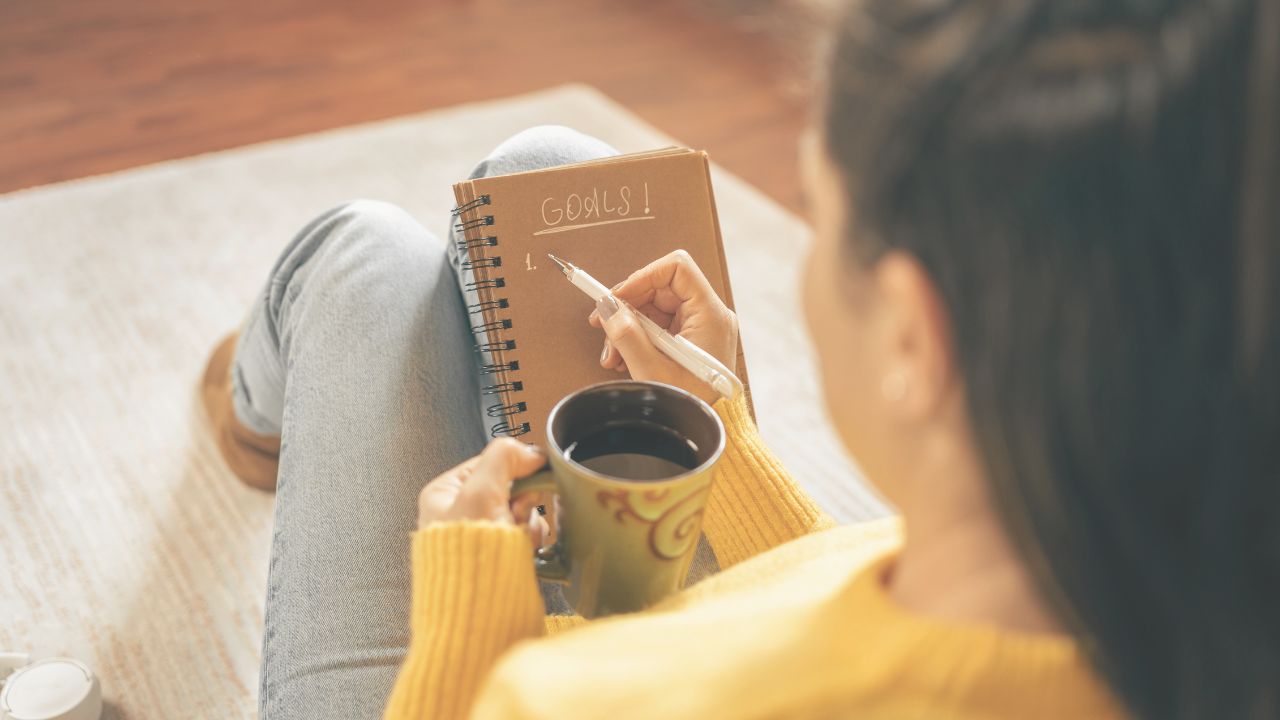 Personne assise avec un carnet, réfléchissant à ses résolutions personnelles en début d'année.
