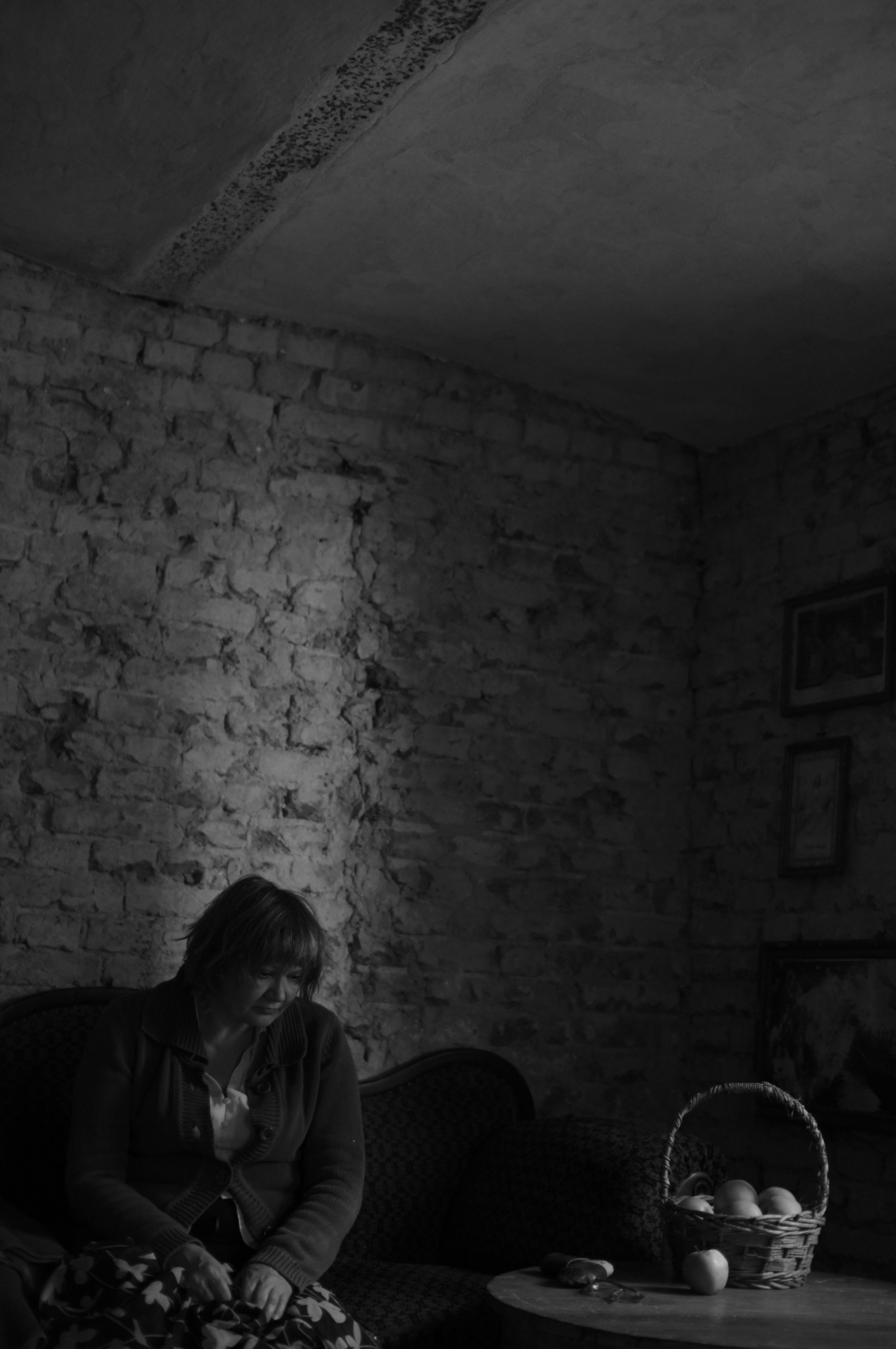 A woman in midlife sits quietly in natural light, looking away from the camera — conveying the internal experience of a transition that is rarely fully seen or named.