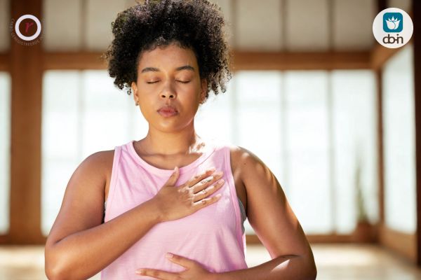 Vrouw in Do-In Yoga-meditatie met hand op hart en buik om vals licht te herkennen en de oorspronkelijke bron te activeren.