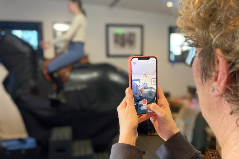 Nadia Molenaers filmt een ruiter op de paardrijsimulator tijdens een workshop.