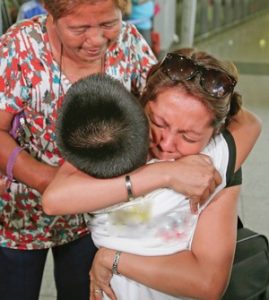 Filipina mother kissing son before departing at the airport for work in abroad