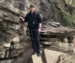 Lance Merrick standing on a rock next to a cliff.