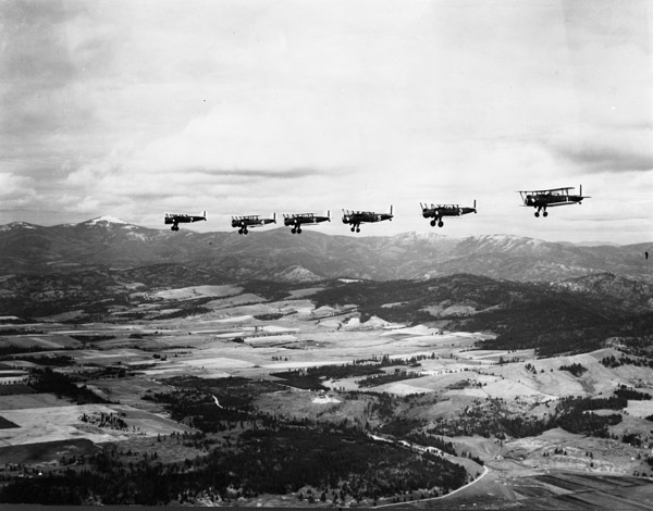Six airplanes, flying in a linear formation, as seen from another airplanne.