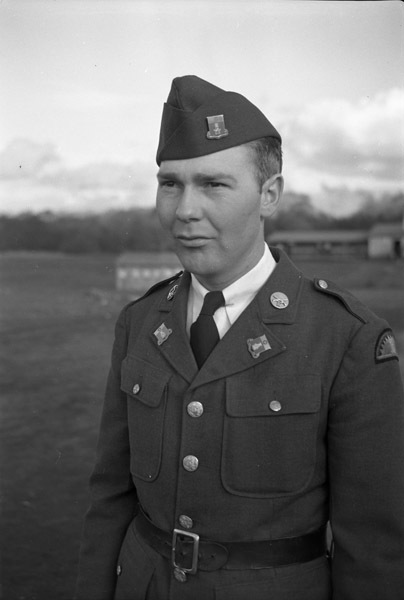 A soldier, seen from the waist up, in dress military attire and a garrison cap.