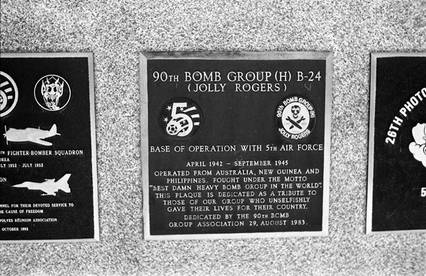 A close-up of a plaque set in a series of plaques.  Other plaques can be seen to the left and right of the centered one.  