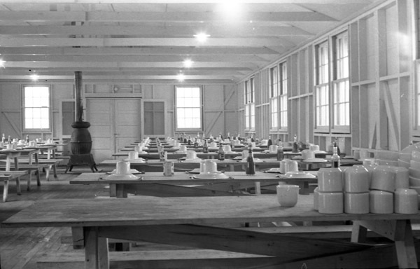 A dining hall with cups and plates upside down and unused on long tables.