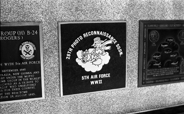 A close-up of a plaque set in a series of plaques. Other plaques can be seen to the left and right of the centered one.
