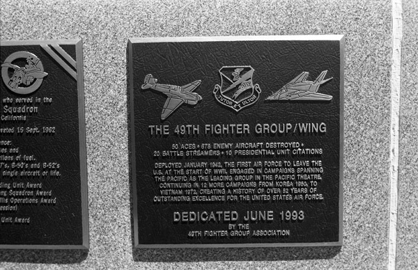 A close-up of a plaque set in a series of plaques.  Other plaques can be seen to the left and right of the centered one.  The caption is in the description.