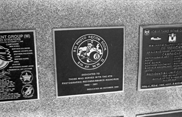 A close-up of a plaque set in a series of plaques. An image in the center shows a caricature of a Native American with a tomahawk in one hand and an eight-ball in the other. Other plaques can be seen to the left and right of the centered one. The caption is in the description.