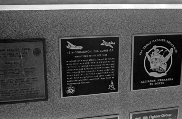 A close-up of a plaque set in a series of plaques.  Other plaques can be seen to the left and right of the centered one.  The caption is in the description, but much of it is hard to read due to lack of camera focus.