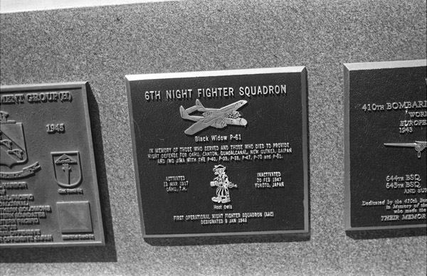 A close-up of a plaque set in a series of plaques.  Other plaques can be seen to the left and right of the centered one. 