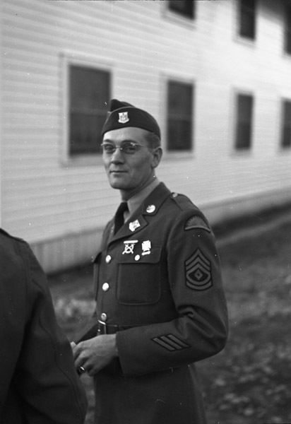 A soldier seen from the waist up in full dress uniform smiling slightly at the camera.