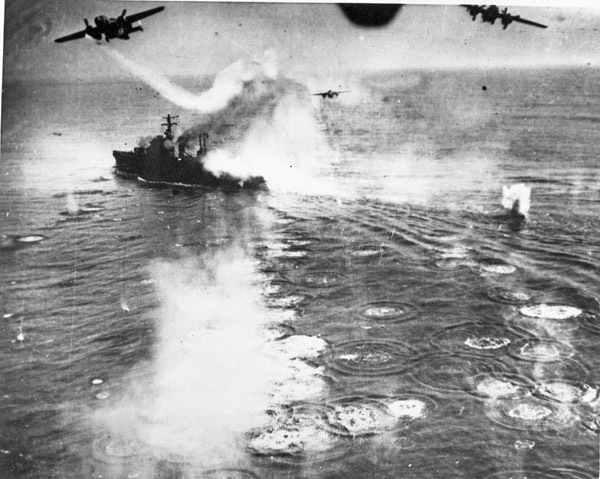 Three bombing planes dropping bombs on a naval battleship on the open water.