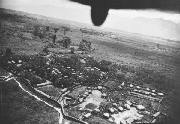 Farming fields and buildings, with the perspective from above in the back of an aircraft.