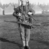 A smiling soldier equipped with multiple rifles, handguns, and swords, most slung over his shoulders and back.  One rifle hangs from his neck, while two handguns are positioned on this belt.
