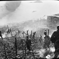 A half dozen soldiers walking down a hill away from the camera that has been cleared of most foliage, possibly by a battle.  Smoke is seen throughout and a destroyed building is seen off to the right.