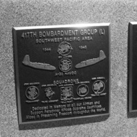 A close-up of a plaque set in a series of plaques.  Other plaques can be seen to the left and right of the centered one.  The caption is in the description.