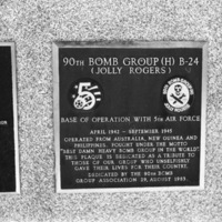 A close-up of a plaque set in a series of plaques.  Other plaques can be seen to the left and right of the centered one.  