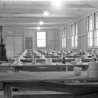 A dining hall with cups and plates upside down and unused on long tables.