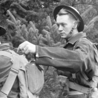 Two soldiers, with the one on the left poking or tickling the soldier on the right on their neck with a stick.  The man on the right is holding up their hand to their neck.