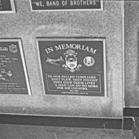 A close-up of a series of memorial plaques.  The central one appears to have one above and to the left of it.