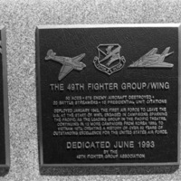 A close-up of a plaque set in a series of plaques.  Other plaques can be seen to the left and right of the centered one.  The caption is in the description.