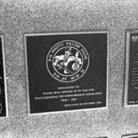 A close-up of a plaque set in a series of plaques. An image in the center shows a caricature of a Native American with a tomahawk in one hand and an eight-ball in the other. Other plaques can be seen to the left and right of the centered one. The caption is in the description.
