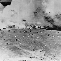 Multiple planes dropping paratroopers to the ground amidst a smoky sky.  