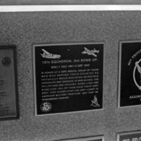 A close-up of a plaque set in a series of plaques.  Other plaques can be seen to the left and right of the centered one.  The caption is in the description, but much of it is hard to read due to lack of camera focus.
