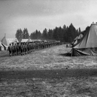 A long line of over a hundred soldiers walking away in formation from the camera angle through a large path in a tent camp.