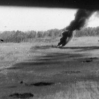 Multiple small craters in an open field, with the rearmost one billowing black smoke.