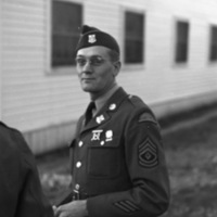 A soldier seen from the waist up in full dress uniform smiling slightly at the camera.  