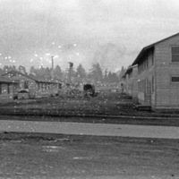 A road with two-story buildings on the right, and single-story buildings on the left.  A truck is on the road, center of image.  