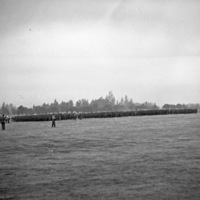 A distant view of dozens, if not hundreds, of soldiers in formation while officers walk in front of them.