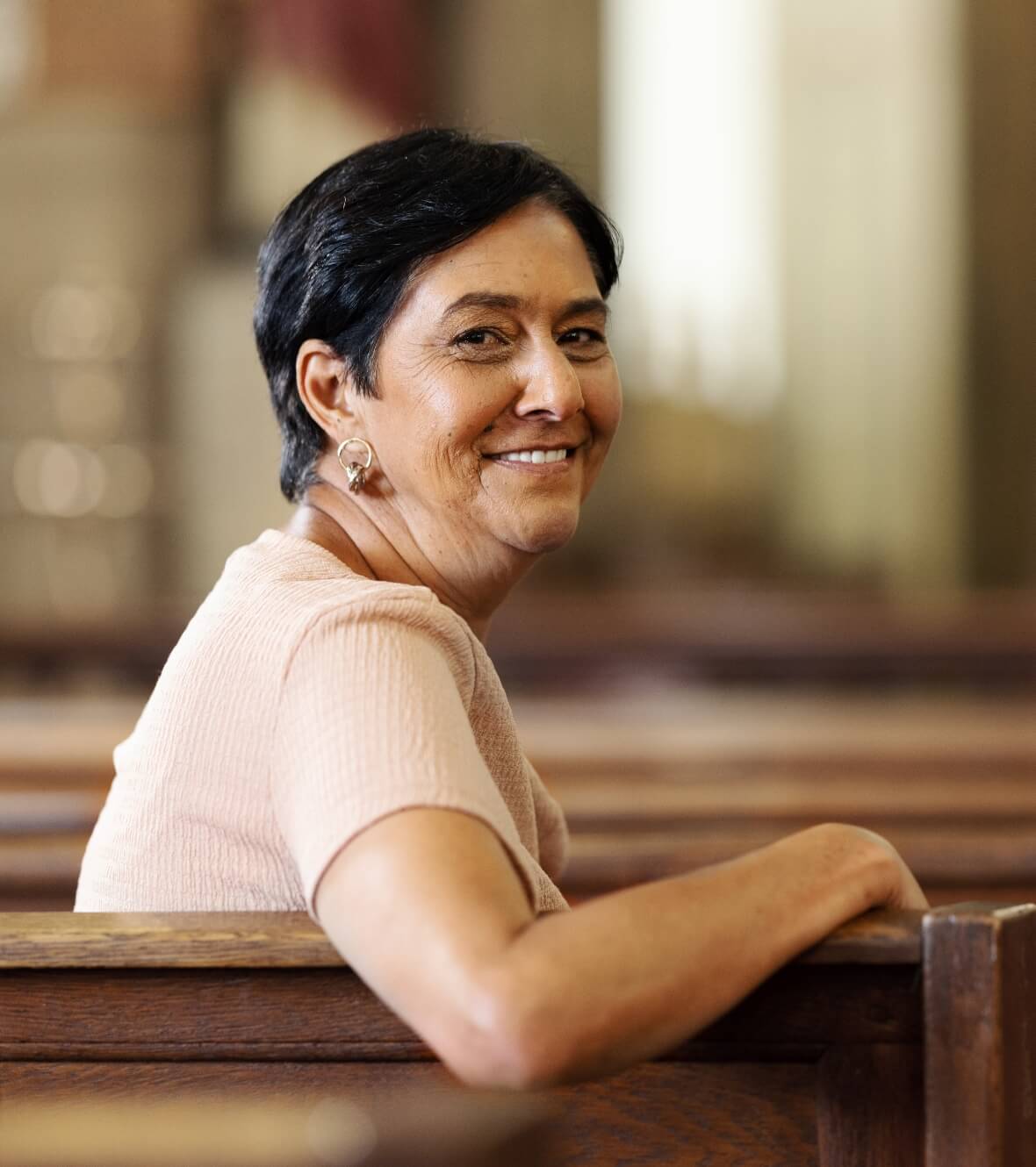 Image showing a woman looking over her shoulder at the camera sitting in the pew of a church.