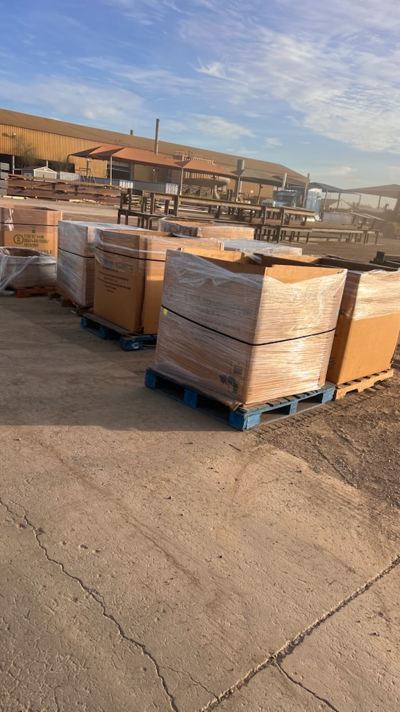 Shrink-wrapped boxes stacked on blue pallets in the yard and ready to ship.