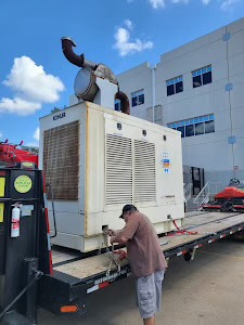 Driver securing an industrial generator on a flatbed trailer.