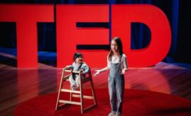 A child stands and gestures on a red circular stage while another sits in a high chair, both framed by large "TED" letters, in a dimly lit auditorium.